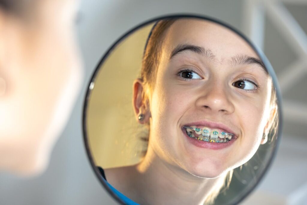 caucasian-preteen-girl-with-braces-her-teeth-looking-mirror_169016-37485